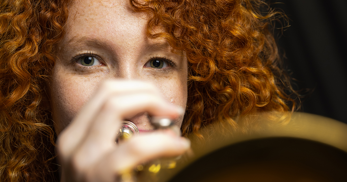 Redhaired girl holding a trumpet, close up